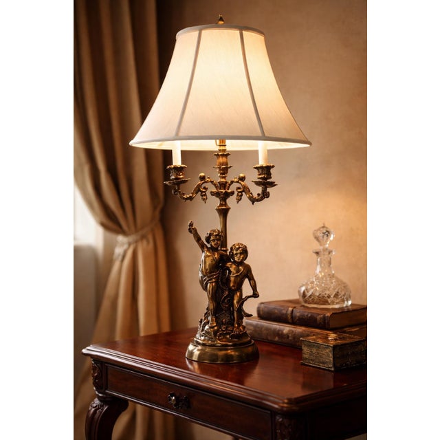 Substantial vintage figural table lamp featuring two classical cherubs supporting a three-arm candle-style light. Executed...