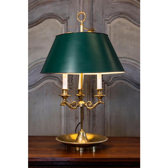 A French brass three-light bouillotte table lamp from the 19th century with green painted tôle shade, bird motifs and...