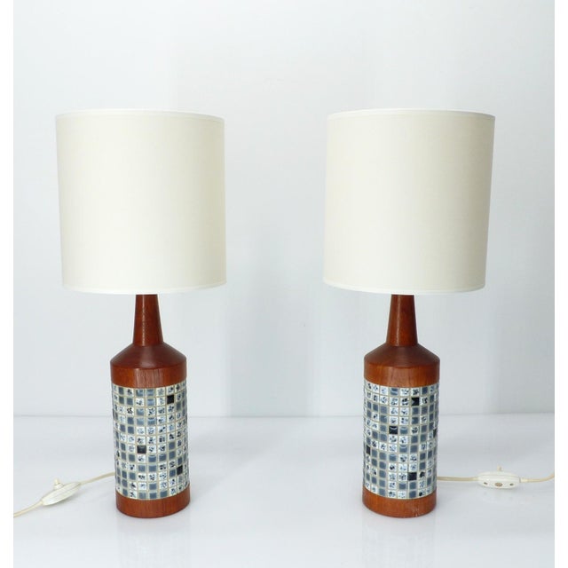 An elegant pair of scandinavian table lamps in solid teak, adorned with a central mosaic band of small glazed ceramic...