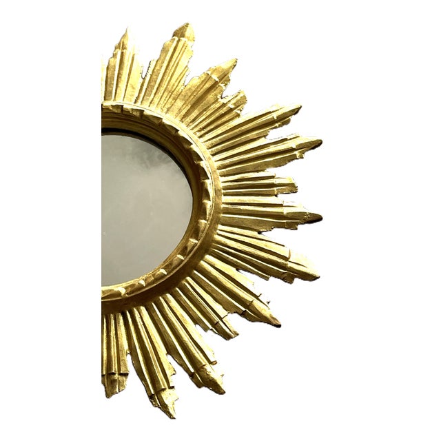 Elegant sunburst mirror in carved and gilded wood, made around 1960. Retaining its original gilding, it boasts a superb...