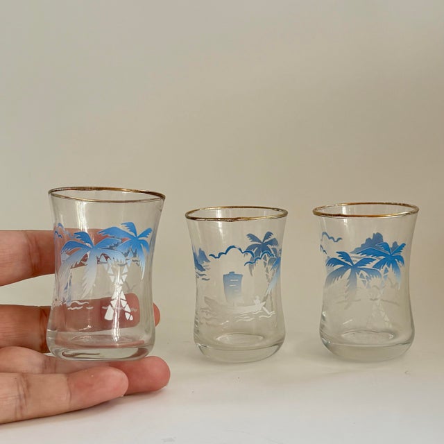 A charming set of three midcentury shot glasses featuring a coastal tropical motif in soft blue and white. Each glass is...