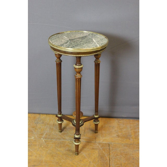 A Louis XVI style mahogany side table with numerous bronze decorations and a green marble top, dating from the Napoleon...