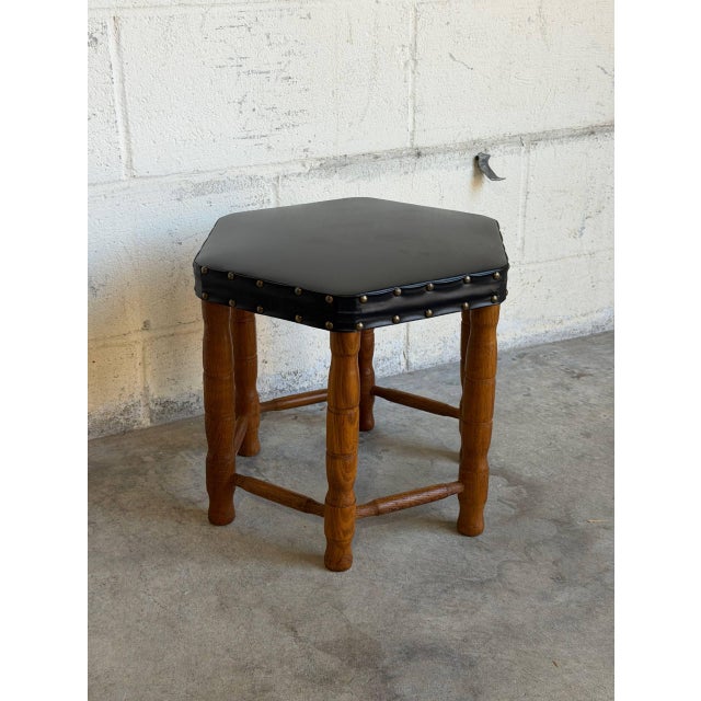 This hexagonal ottoman features a black padded seat with brass nailhead trim along the border. Its unique geometric...