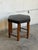 This hexagonal ottoman features a black padded seat with brass nailhead trim along the border. Its unique geometric...