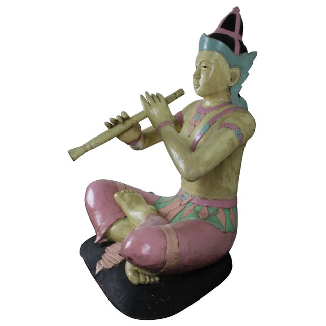 "A large wooden sculpture of the famous Prince Phra Aphai Mani playing his magic flute, Thailand. Finely decorated with...