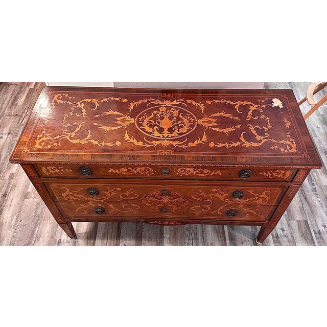 This piece is an ornate Neoclassical-style marquetry commode (chest of drawers); 18th century Italian, with wooden inlay....