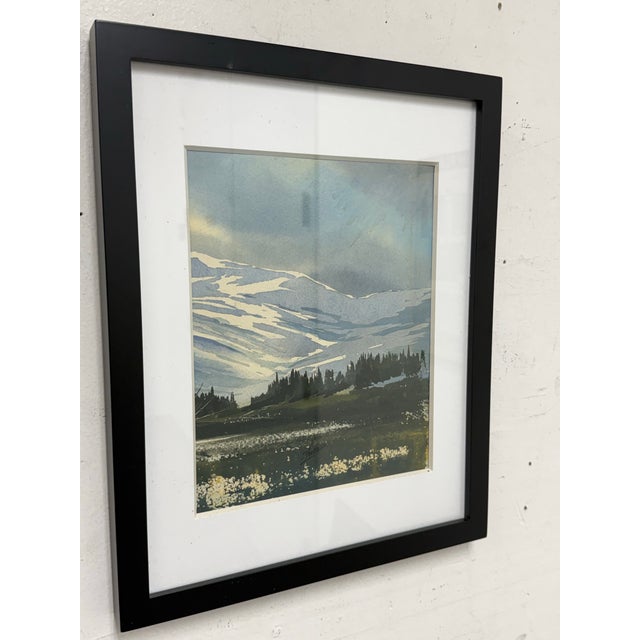 Design Plus Gallery presents a Signed Watercolor of the Valley of a Mountainside. White snow capped mountains are in the...