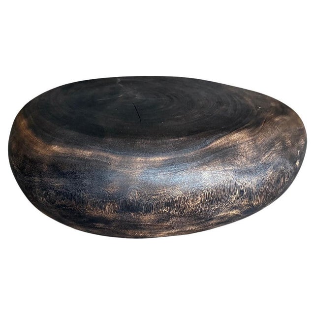 A minimalist pebble style low profile coffee table. Hand carved from a single piece of suar wood. Charred a rich brown...