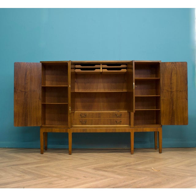 A 1960s Continental walnut highboard cabinet with beautifully figured book-matched veneers, elegant tapered legs and a...
