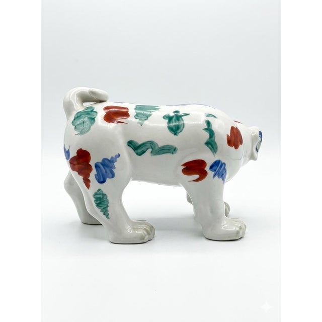 Description: Charming, hand-painted ceramic dog figurine featuring a whimsical folk art style. Glazed in a glossy white...