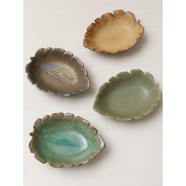 A set of four leaf-shaped ceramic small dishes; each is modeled in the form of a leaf with a natural, serrated edge, and...