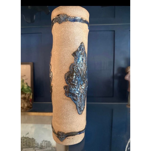 This vintage ceramic vase features a unique rectangular shape with textured beige surface and ornate blue floral accents...