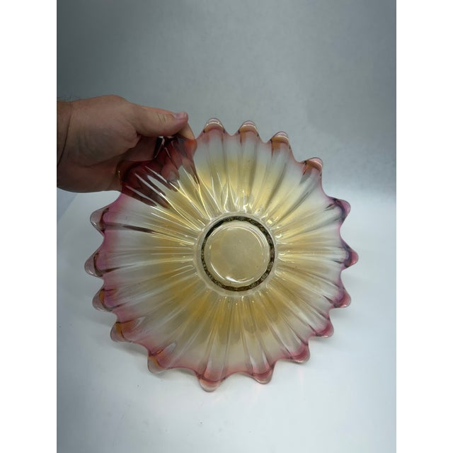 An elegant vintage art glass bowl featuring a striking pleated or starburst form with a dramatic ruffled, scalloped rim....