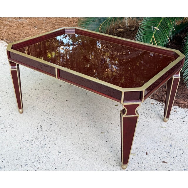 Glamorous and sophisticated deep burgundy lacquered coffee table with gold trim. This high style coffee table is...