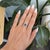 A captivating teal sapphire blends ocean blue and forest green at the center of this oval ring, framed by a halo of...