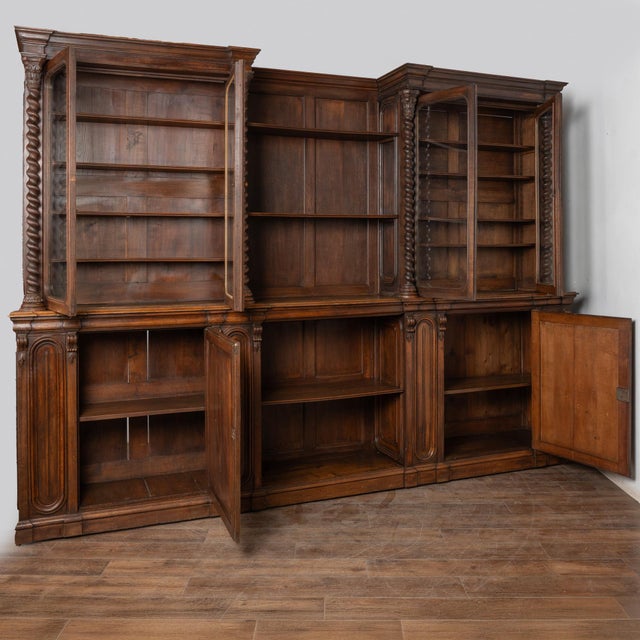 Late 19th-century French oak bookcase or display cabinet featuring dramatic scale and carved detail. The cabinet is framed...
