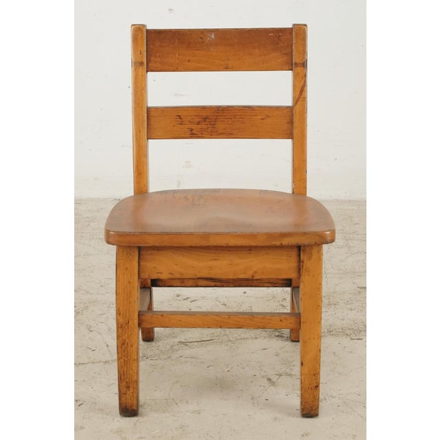 Vintage Shaker style children’s chair in medium toned wood. Straight legs, slats, and stretchers are softened by a slight...