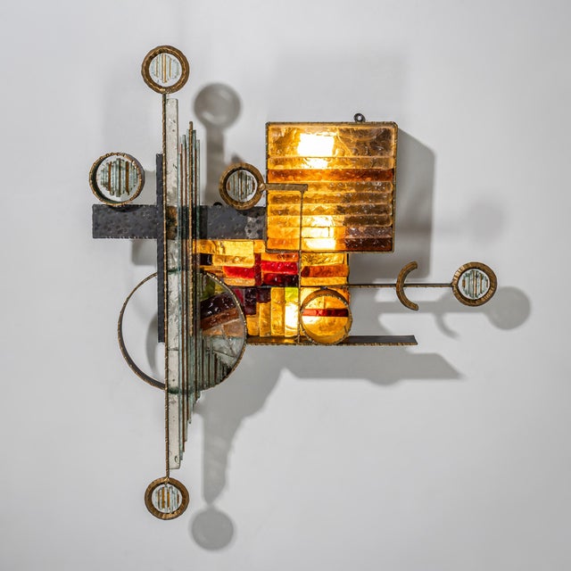 Large sculptural wall light in the Brutalist style featuring circular elements and amber-colored glass inserts in varying...