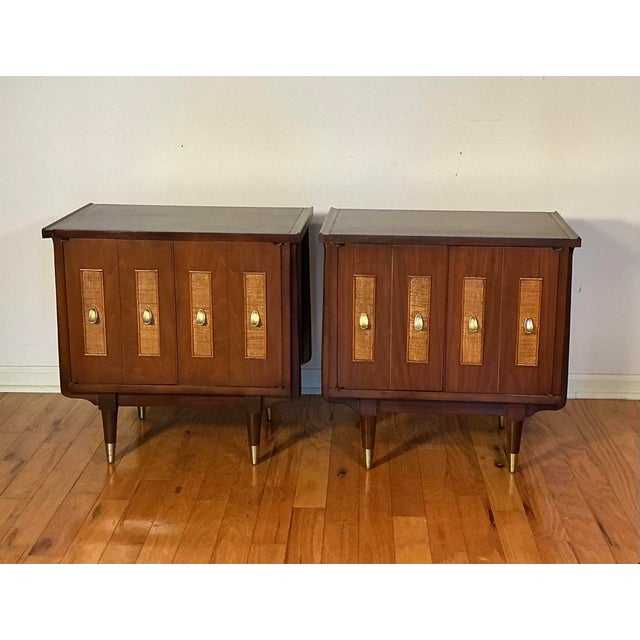 Pair of Mid Century Modern nightstands from the 1960's. Cane panels on the doors with unique brass shaped pulls, with...