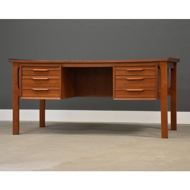 A mid century modern teak double bank desk with sculpted pulls, lipped top and a finished back. Made in Denmark....