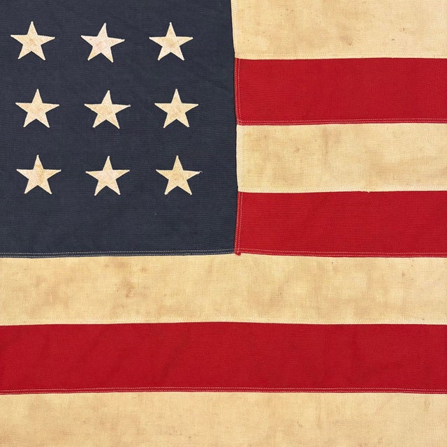 This vintage American flag is made from a cotton cloth with fully sewn stars and stripes. Please note overall staining and...