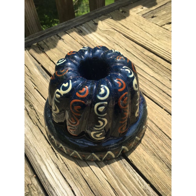 This is a French earthenware slip-decorated mold in blue, reddish brown and cream. The inside is glazed a reddish brown....