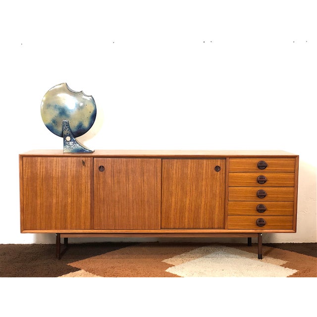 A 1960s Italian-made sideboard made entirely of teak veneer, restored and sanitized, featuring two sliding doors with...
