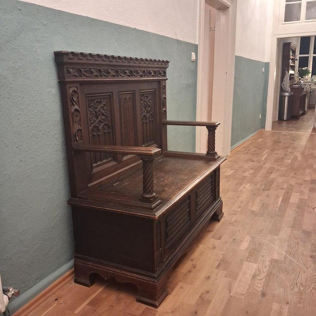Massive neo-Gothic oak chest bench, circa 1880–1910. Richly carved with tracery, grapevine ornamentation, and crenellated...