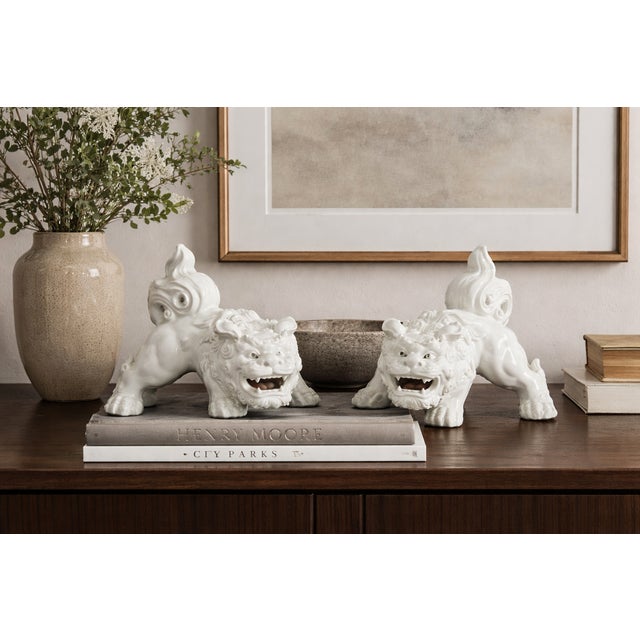 A sculptural pair of mid-20th century Japanese porcelain guardian lions (often called “foo dogs”), rendered in luminous...