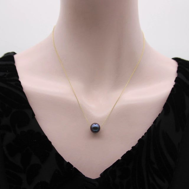 This 14k gold necklace has a minimal and sophisticated look with a black South Sea pearl as its centerpiece. The black...