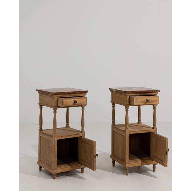 A pair of oak side tables with marble tops and sturdy frames. The combination of materials provides contrast and...