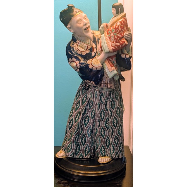This is a vintage table lamp crafted from a hand-painted Japanese ceramic figurine mounted on a turned wooden base. Key...