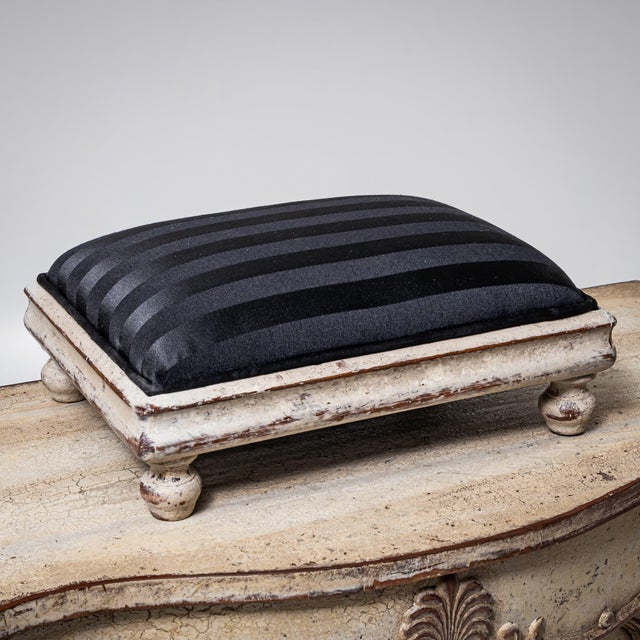 Small decorative footstool on turned baluster legs with a rectangular molded frame. Newly upholstered and covered in a...