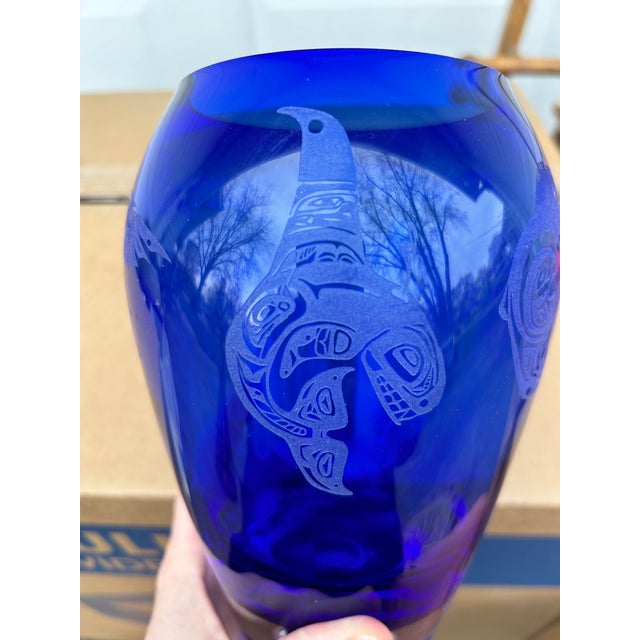 This blue glass etched vase is signed "Coyle." It features etchings or engravings of Haida indigenous killer whale, eagle,...