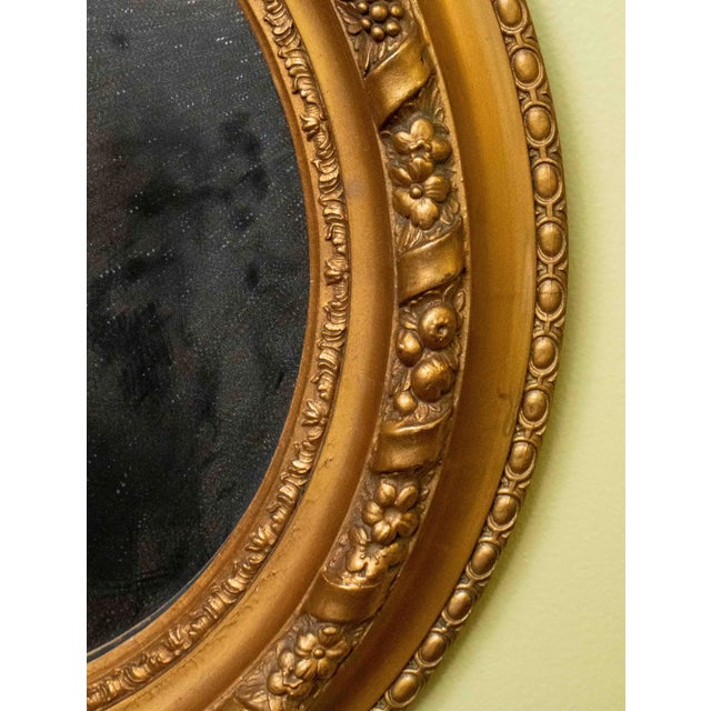 Beautiful pair of antique gilded wood and gesso oval mirrors. The gilding retains a warm, aged patina with light wear,...