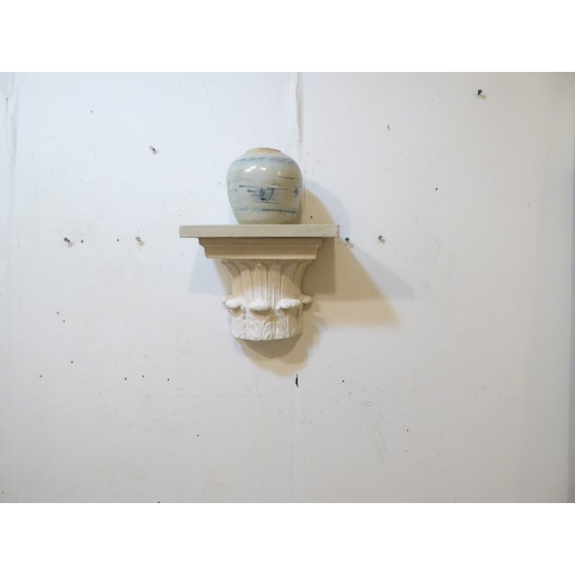 This classical style bracket is plaster with a wooden top.