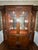 A china display cabinet in the Regency style by Henredon. Mahogany with inlaid flame mahogany, unique curved inward sides...