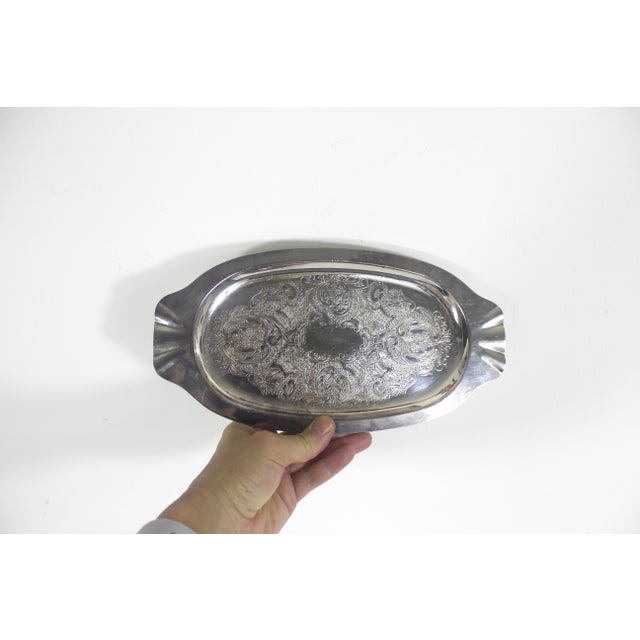 Small vintage oval silver plated tray with gorgeous floral detail embossed or engraved base. The ends have flared, fan...