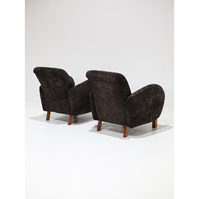 Two beautiful armchairs produced in Denmark, c1940s, featuring large, rounded armrests and a subtle curve in the backrest...
