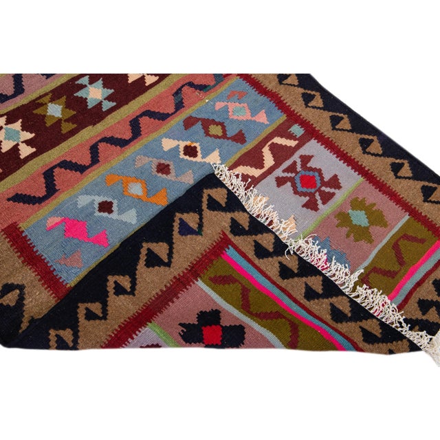 Beautiful vintage Turkish Kilim hand-knotted wool runner with a red field. This rug has a brown frame and multicolor...