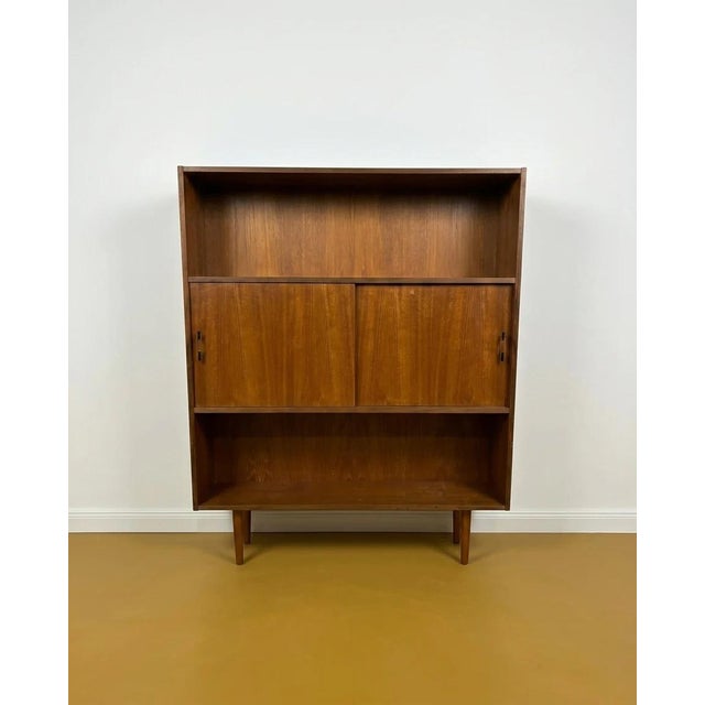 Vintage 1950s Danish teak bookcase with sliding doors and open shelves, a functional design perfect for mid-century decor....