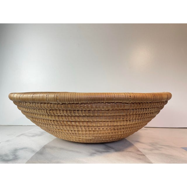 Handwoven coiled rattan charger or shallow basket bowl crafted from natural fibers such as rattan, seagrass, or coiled...