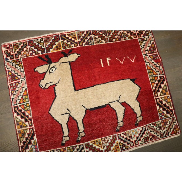 a 3rd quarter of the 20th century Gabbeh Rug depicting a deer on a madder red field