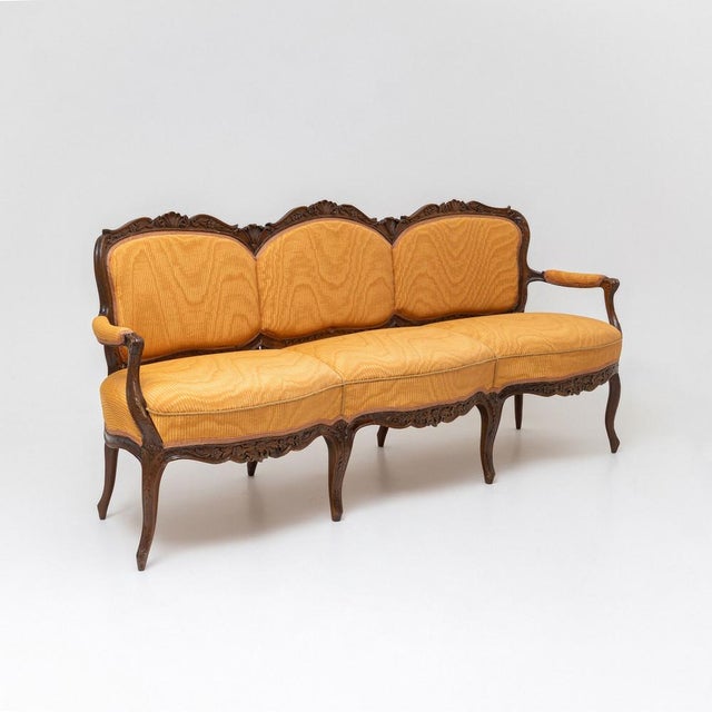 A Baroque-style three-seater sofa crafted from walnut in the 2nd half 19th century. The curved backrest and apron are...