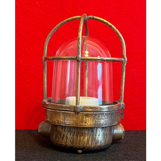 Vintage industrial lamp with an authentic character, crafted with a brass-colored metal body, a thick, bell-shaped glass...