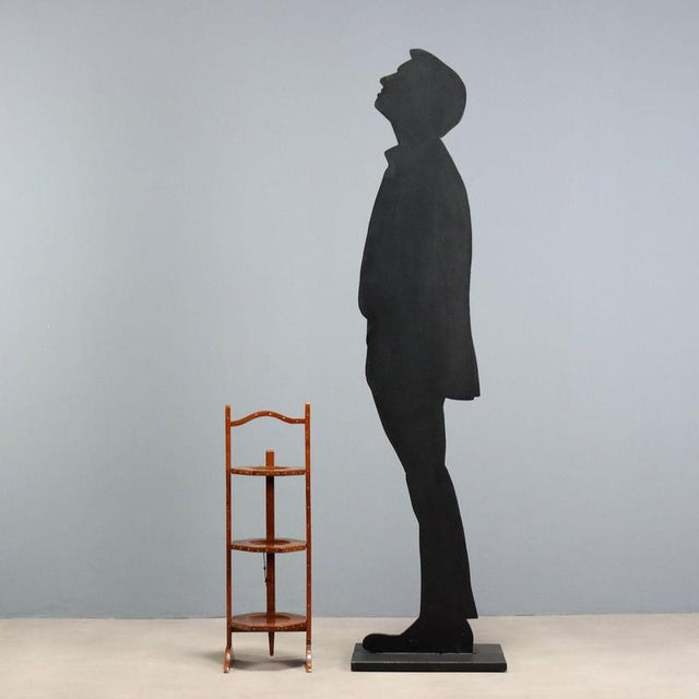 Walnut valet stand with brass trim and inlays. Three octagonal, revolving tray shelves supported by lateral legs with...