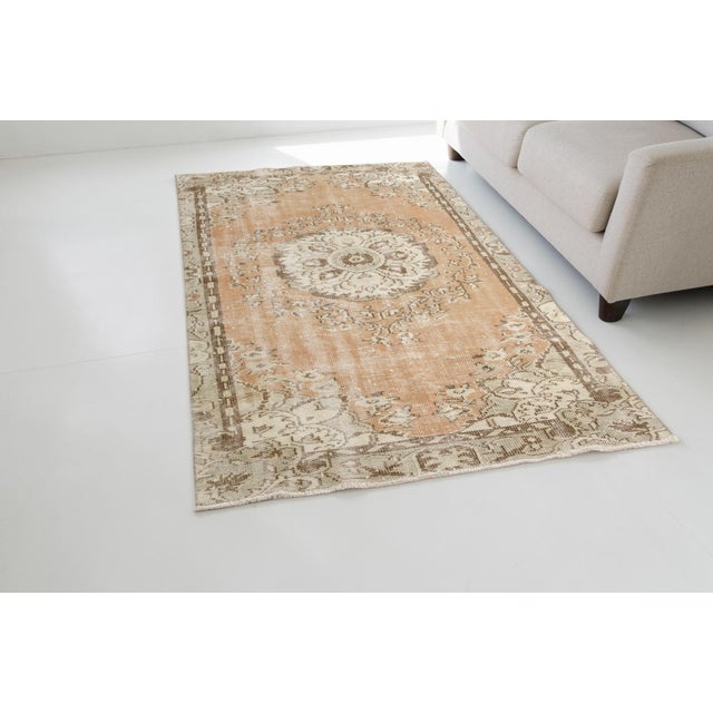 This is a vintage Turkish Oushak rug from the Mid 20th Century. The piece was hand-knotted.