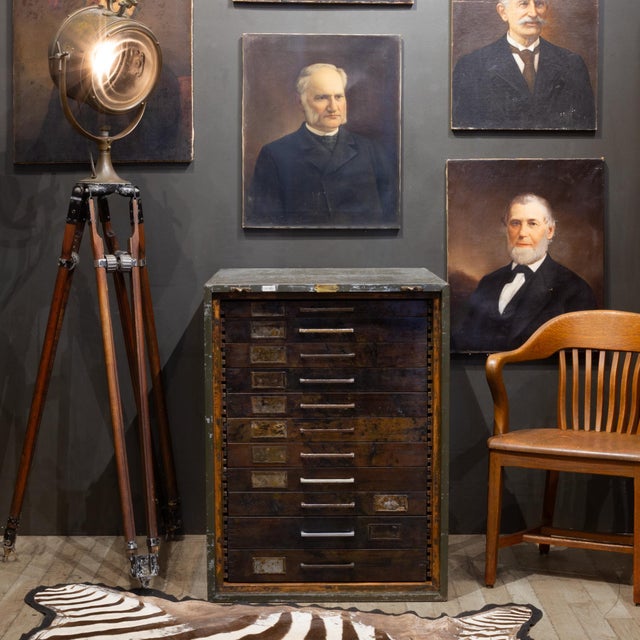 ABOUT An early 20th century flat file cabinet with eleven deep drawers, large metal pulls, two brass plated hooks and...