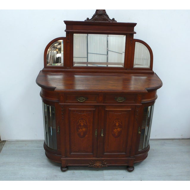 Antique sideboard / chiffonier with mirrored top and rounded sides made of solid oak, featuring inlays and ornamental...