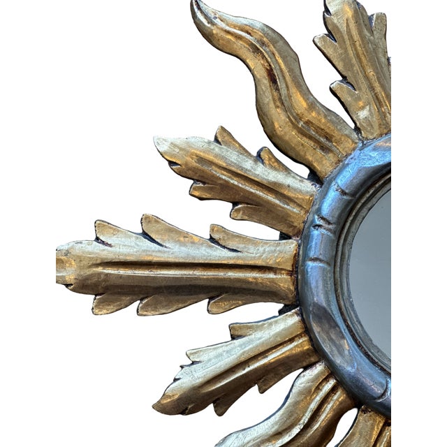 A radiant Italian giltwood mirror in the form of a stylized sunburst, crafted circa 1940s. Carved with alternating flamed...